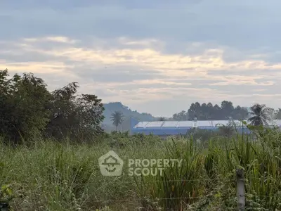 Scenic view of lush greenery with distant building under a cloudy sky, perfect for serene living.