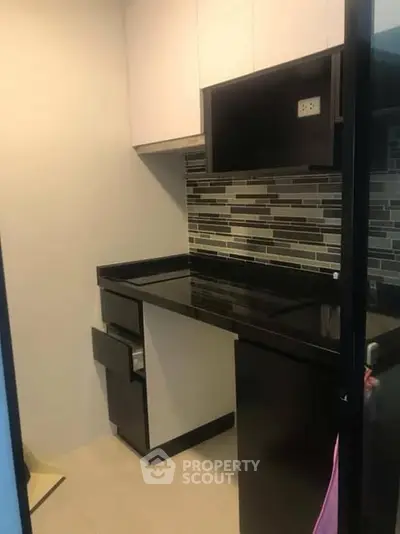 Modern compact kitchen with sleek black countertops and stylish backsplash