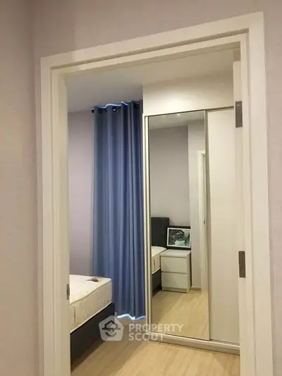 Modern bedroom with mirrored closet doors and elegant blue curtains