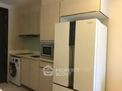 Modern kitchen with sleek appliances including fridge, oven, and washing machine in compact layout.