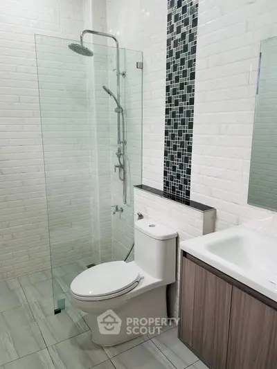 Modern bathroom with glass shower and sleek fixtures in contemporary design.
