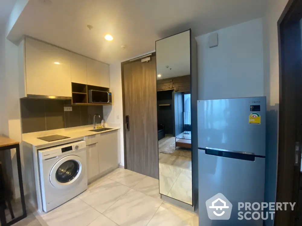 Modern compact kitchen with washing machine and fridge in stylish apartment