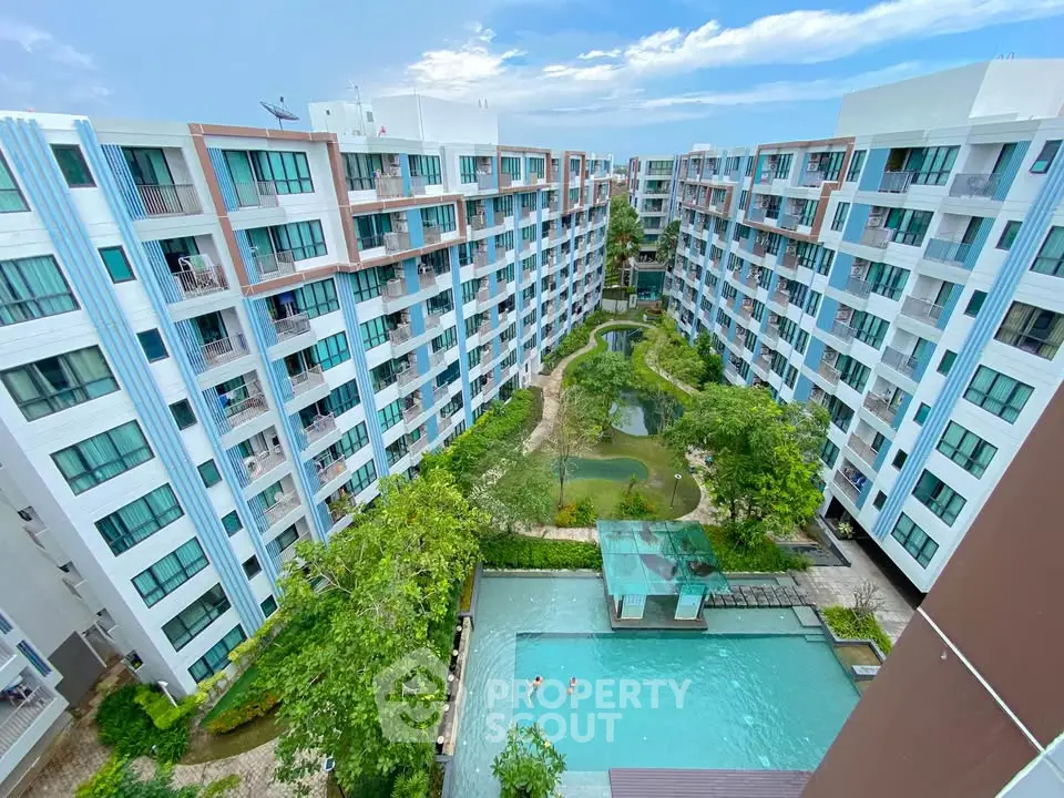 Stunning aerial view of modern apartment complex with lush gardens and inviting pool area.