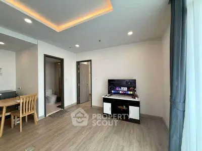 Modern living room with sleek design and open layout, featuring a TV and dining area.