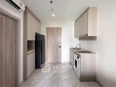 Modern kitchen with sleek cabinetry, washing machine, and refrigerator in a compact layout.