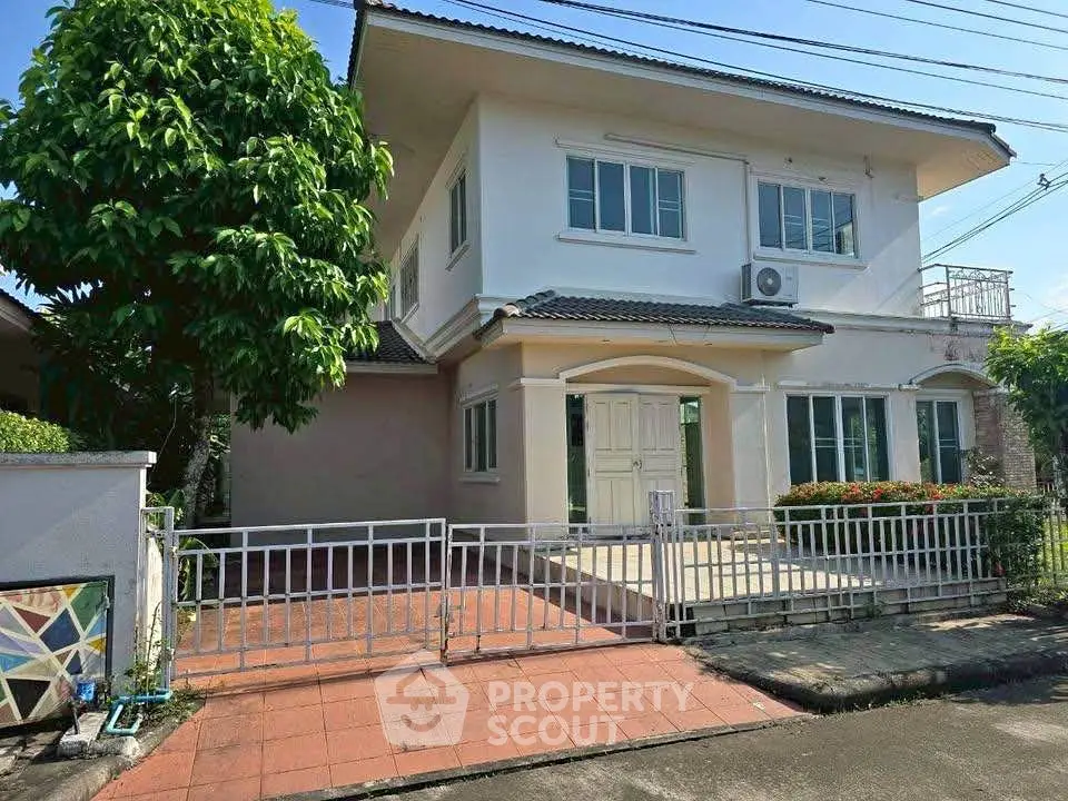 Charming two-story house with gated entrance and lush greenery