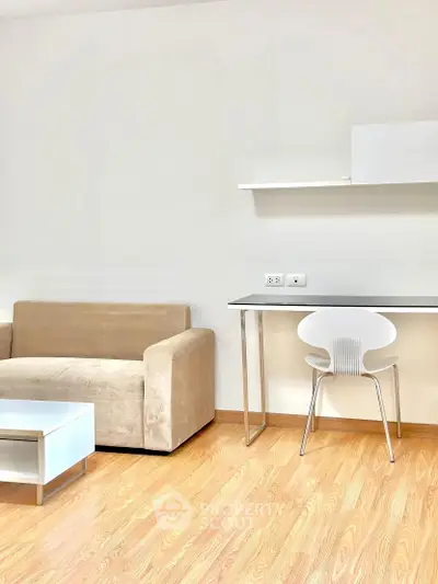 Modern minimalist living room with beige sofa and sleek desk setup.