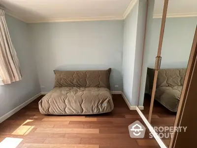 Cozy bedroom with wooden flooring and mirrored wardrobe