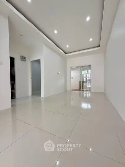 Spacious modern living room with sleek tile flooring and recessed lighting, perfect for contemporary living.