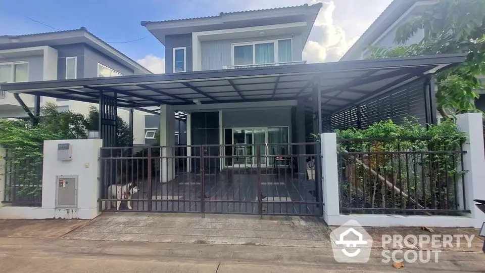 Modern two-story house with gated entrance and covered carport in suburban neighborhood.