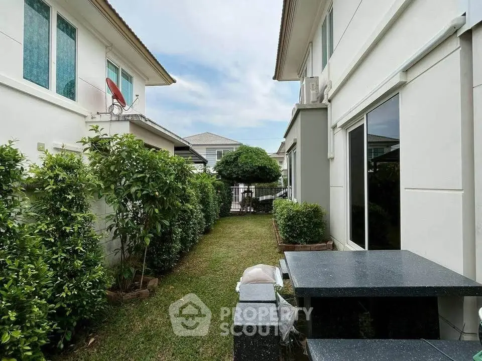 Charming garden space between modern homes with lush greenery and outdoor seating.