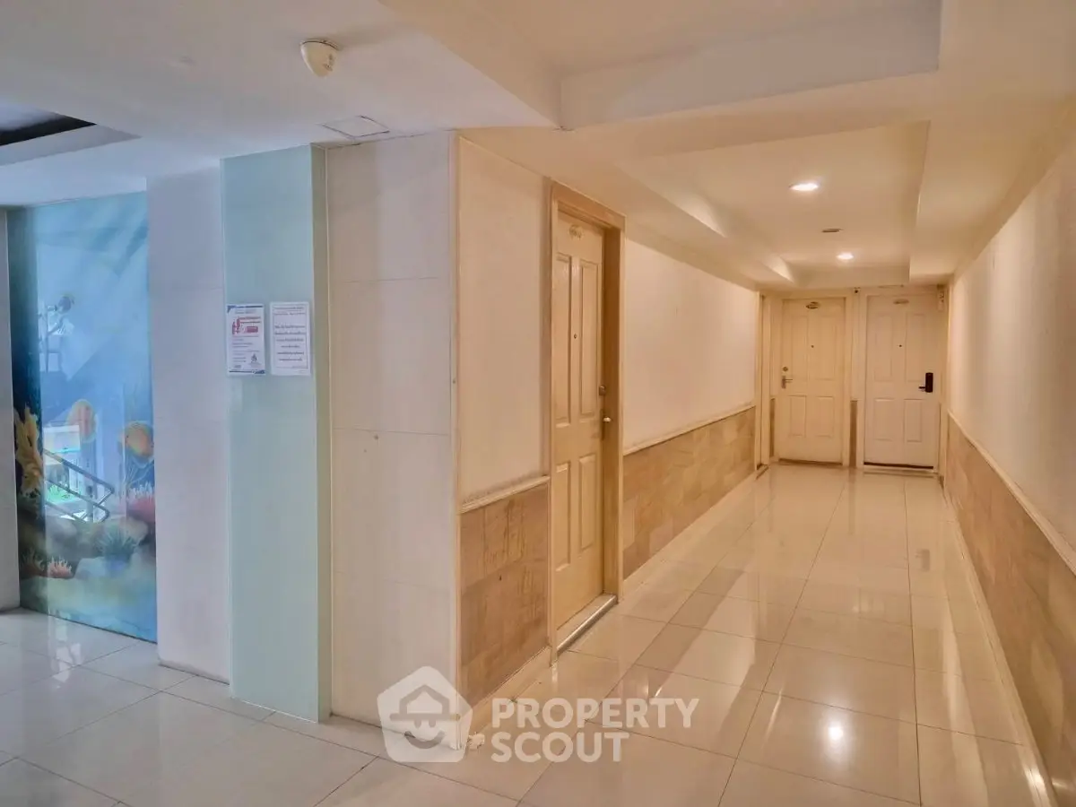 Modern apartment corridor with polished tiles and bright lighting.
