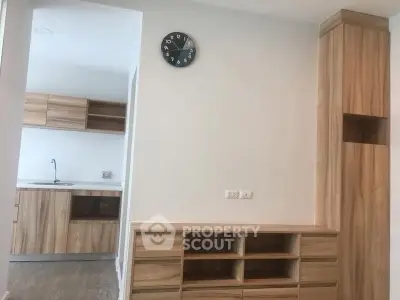 Modern kitchen with wooden cabinets and wall clock in a minimalist apartment
