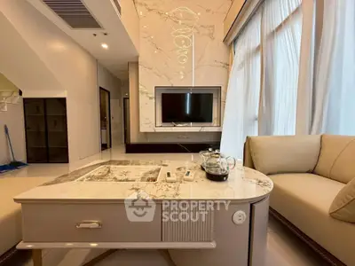 Luxurious living room with marble accents and modern furniture, featuring a stylish TV setup and elegant lighting.