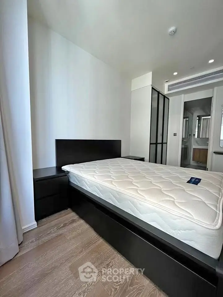 Modern bedroom with sleek design and natural light, featuring a comfortable bed and stylish furniture.