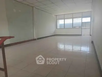 Spacious empty room with tiled flooring and large windows, ideal for office or studio setup.