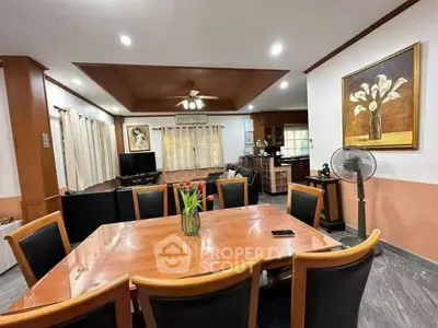 Spacious dining area with elegant wooden table and chairs, adjacent to cozy living room with modern decor.