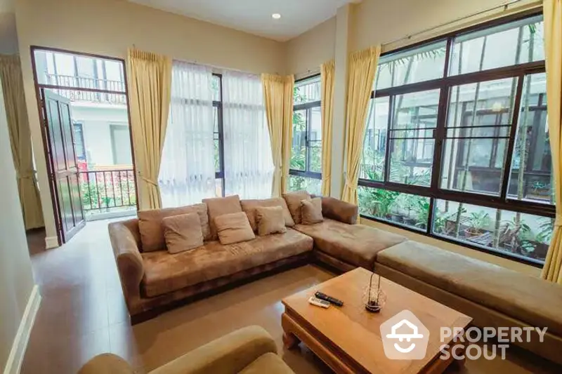 Spacious living room with plush seating and large windows offering ample natural light, perfect for relaxation and entertaining guests.