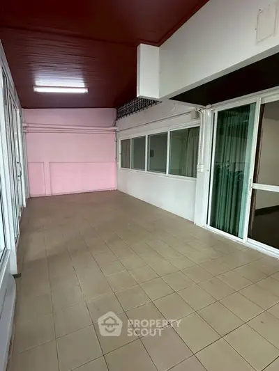 Spacious tiled balcony with sliding glass doors and pink accent wall