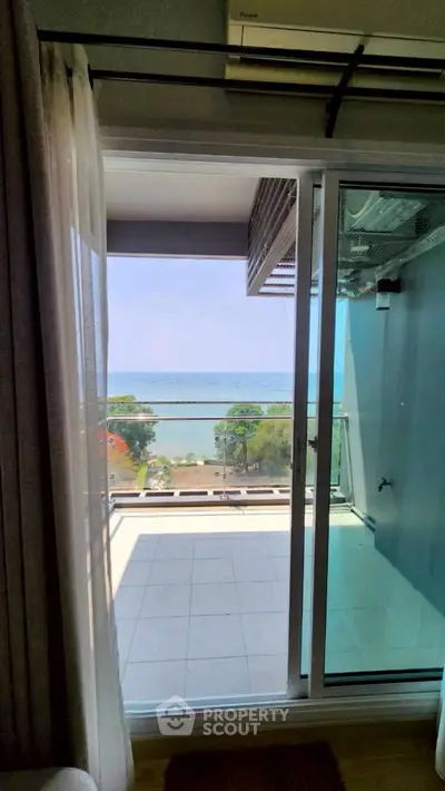 Stunning ocean view from modern apartment balcony with sliding glass doors.