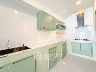 Modern kitchen with green cabinets and gas stove in a bright, spacious layout.