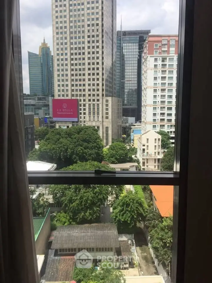 Stunning cityscape view from high-rise window with lush greenery and modern architecture.