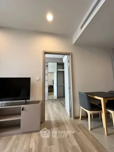 Modern apartment interior with open living and dining area, featuring sleek furniture and wooden flooring.