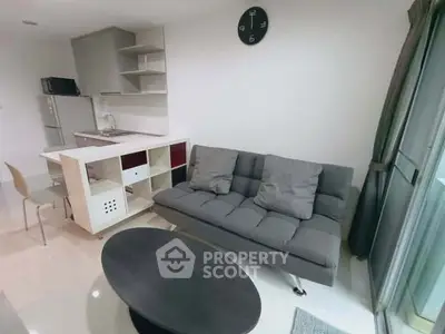 Modern living room with sleek kitchen and cozy sofa in open layout apartment.