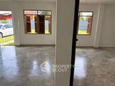 Spacious open-plan interior with polished concrete floors and large windows, ideal for natural light.