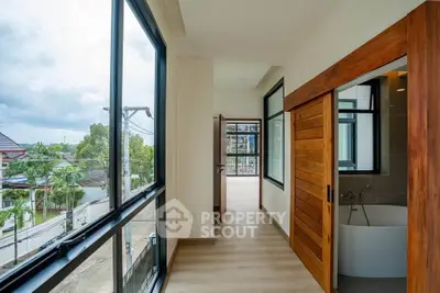 Modern hallway with large windows and wooden sliding doors, offering a glimpse of a luxurious bathtub.