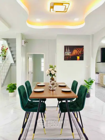 Elegant dining area with modern decor and stylish green chairs in a bright, open-plan home.
