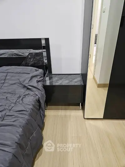 Modern bedroom with sleek black furniture and wooden flooring