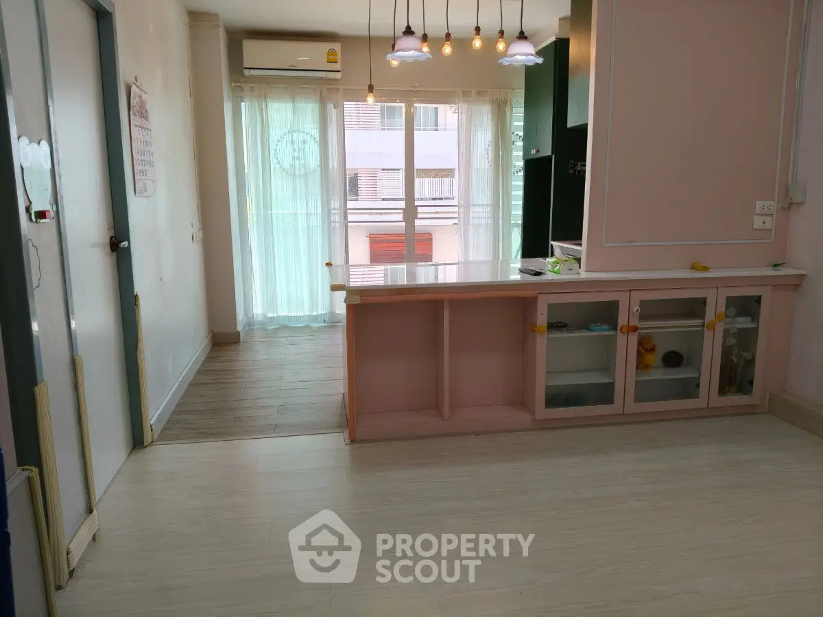 Charming open-plan living space with large windows and modern lighting fixtures.