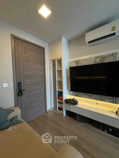 Modern living room with sleek TV setup and air conditioning, featuring stylish wooden flooring and contemporary decor.