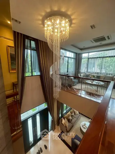 Luxurious two-story living room with elegant chandelier and large windows