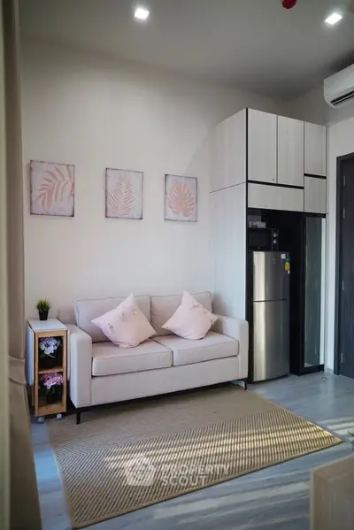 Modern living room with stylish decor and compact kitchen area, featuring a cozy sofa and sleek appliances.