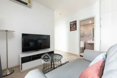 Modern living room with sleek furniture and a glimpse of a stylish bathroom.