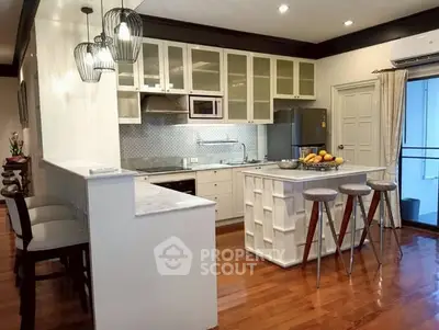 Modern kitchen with island, bar stools, and sleek appliances in open layout.