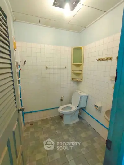 Cozy bathroom with tiled walls and floor, featuring a toilet and shower area, ideal for compact living spaces.