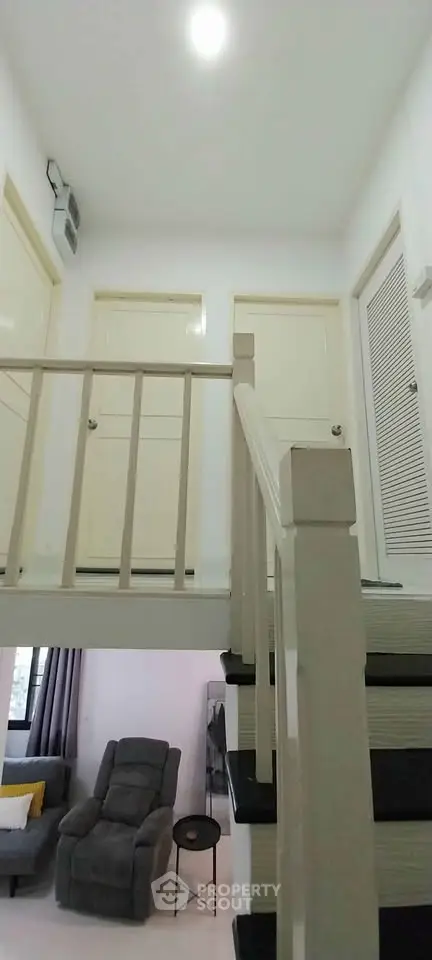 Modern interior with staircase and cozy living area, featuring a recliner and stylish decor.