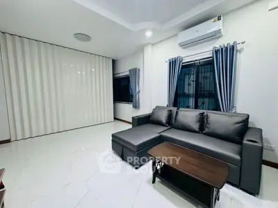 Modern living room with sleek gray sofa and air conditioning, featuring elegant curtains and glossy tiled flooring.