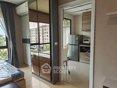 Modern apartment interior with mirrored wardrobe and compact kitchen area.