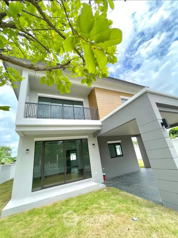 Modern two-story house with large windows and a spacious lawn, perfect for family living.
