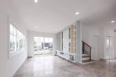Spacious modern living room with large windows and elegant staircase