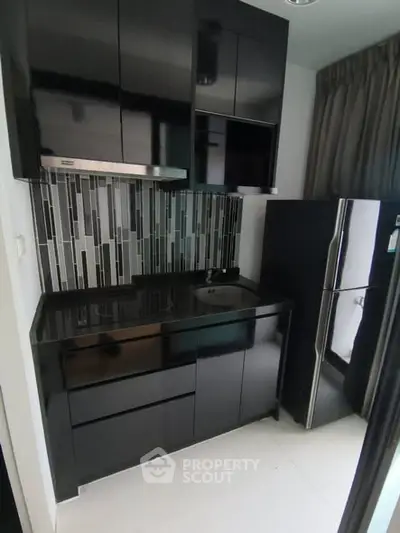 Modern compact kitchen with sleek black cabinets and stylish backsplash