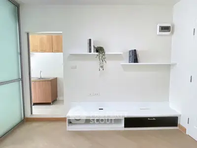 Modern minimalist living room with built-in shelves and adjacent kitchen area.
