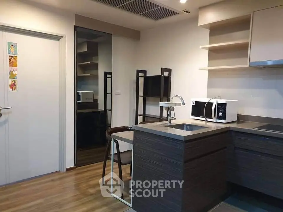 Modern kitchen with sleek design and compact layout featuring microwave and induction cooktop.