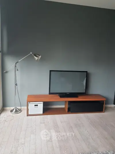 Modern living room with sleek TV stand and stylish floor lamp on wooden flooring.