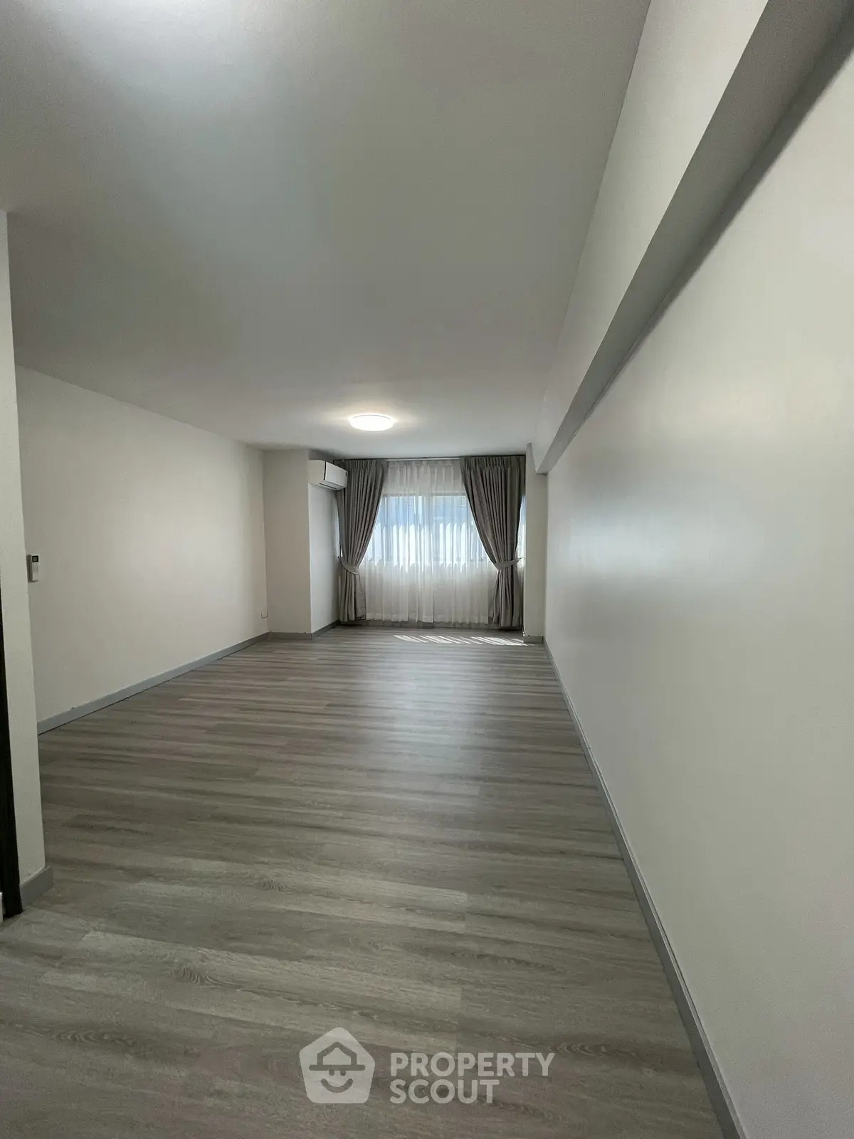 Spacious empty room with large window and elegant curtains, perfect for customization.