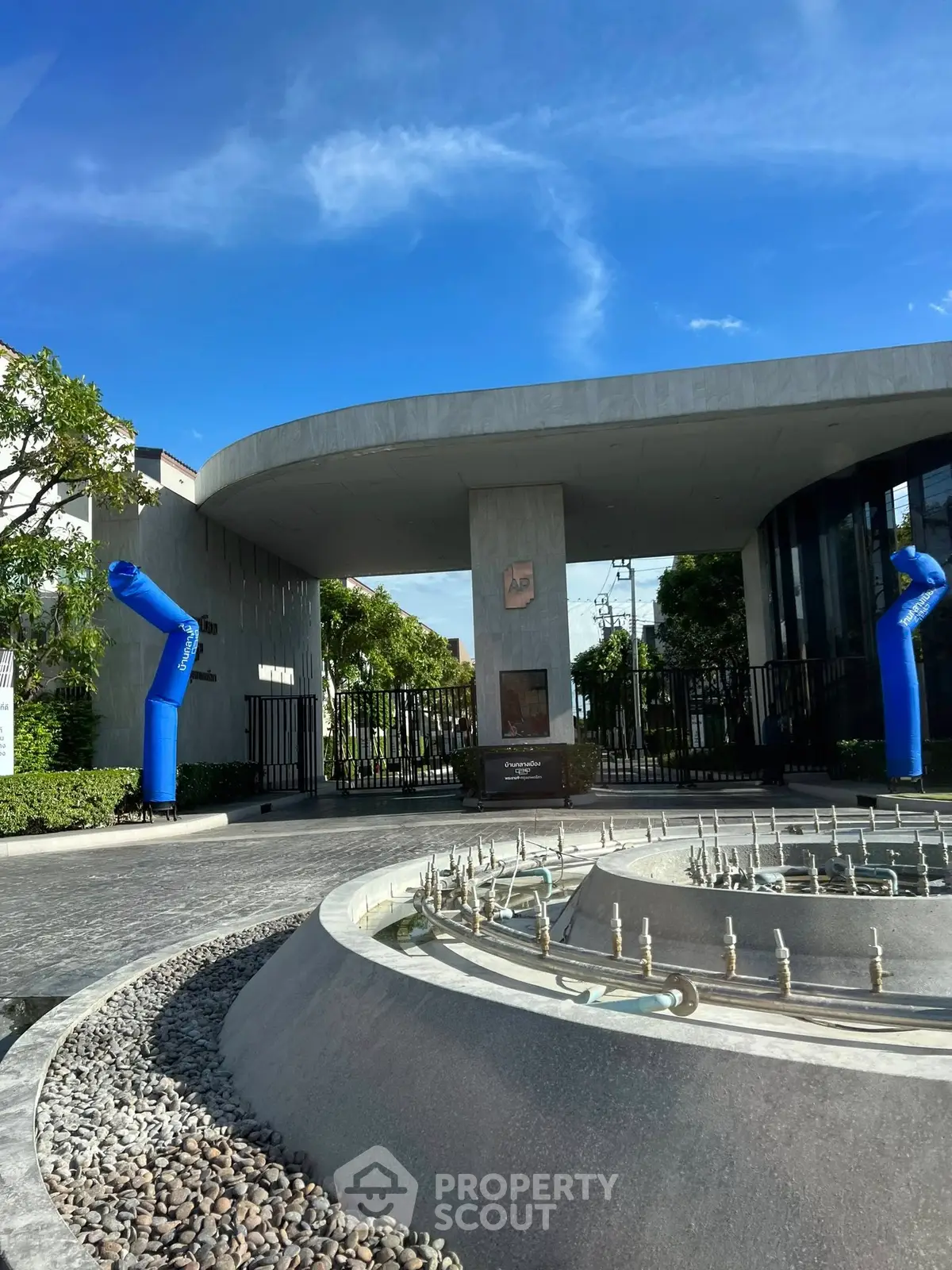 Modern building entrance with unique architectural design and fountain feature under a clear blue sky.